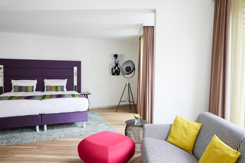 杜塞道夫的住宿－杜塞爾多夫勝利廣場靛藍酒店，一间卧室设有一张大床和一张红色凳子