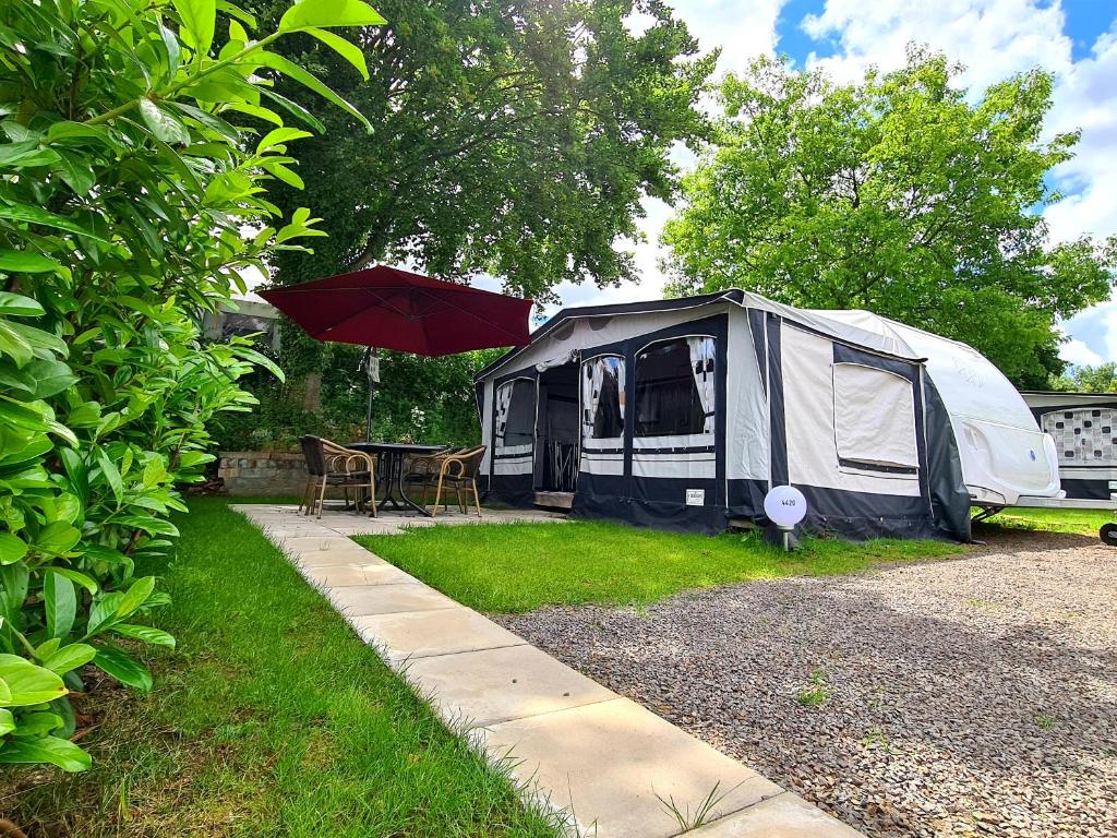 a tent with a table and an umbrella in a yard at Campingplatz Hof Biggen in Attendorn