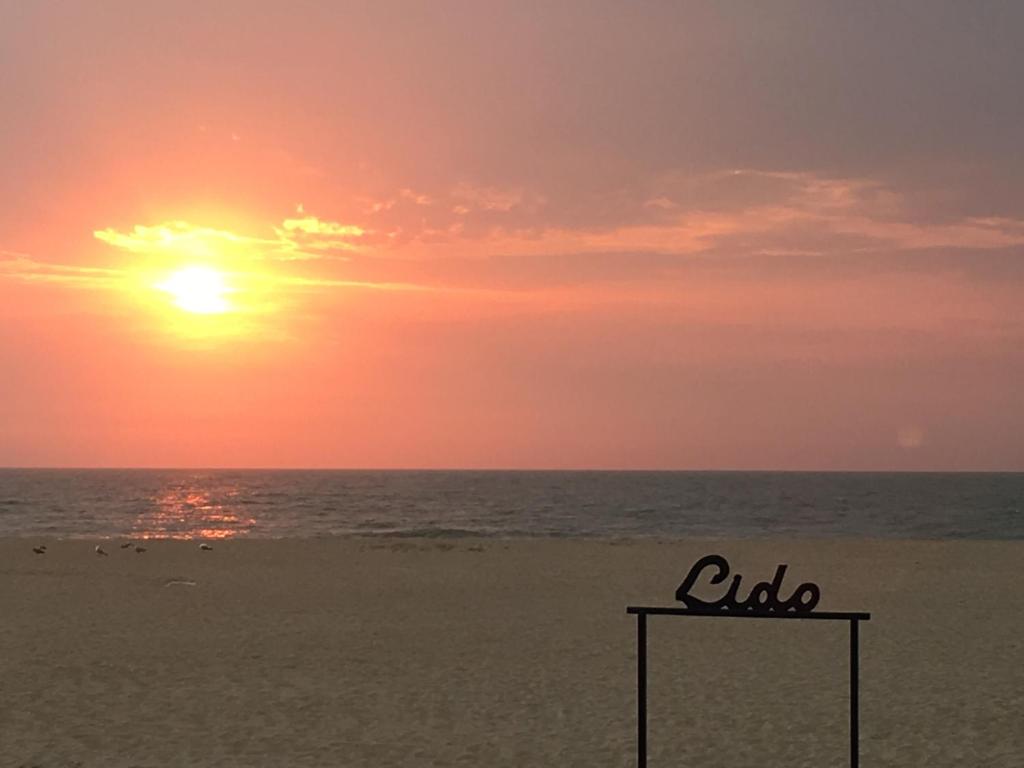 una puesta de sol en la playa con un cartel en la arena en Theodore Oostende-zorgeloos genieten in stijl op de perfecte locatie en Ostende