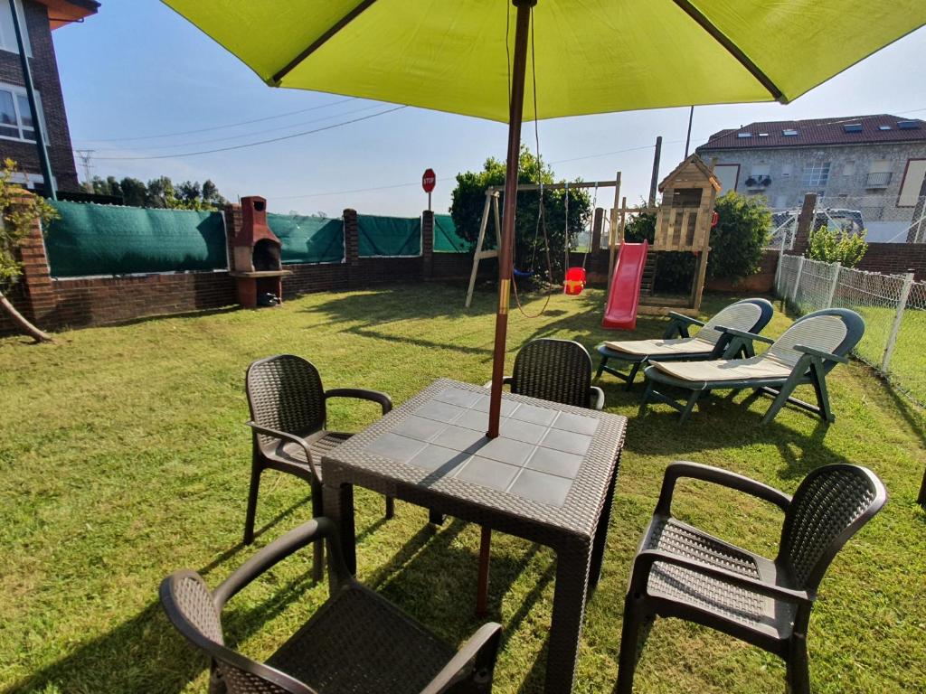einen Tisch und Stühle mit Sonnenschirm im Hof in der Unterkunft El Mirador de Suances in Suances