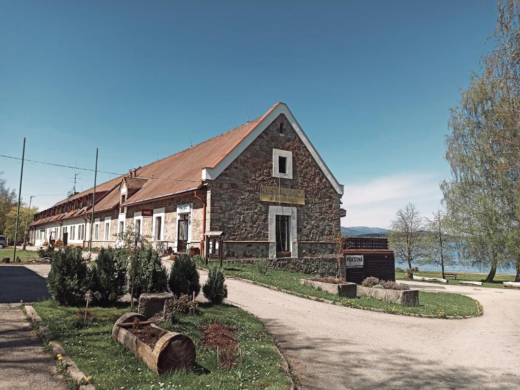 un gran edificio de piedra con una carretera delante de él en Hotel Jestřábí en Černá v Pošumaví