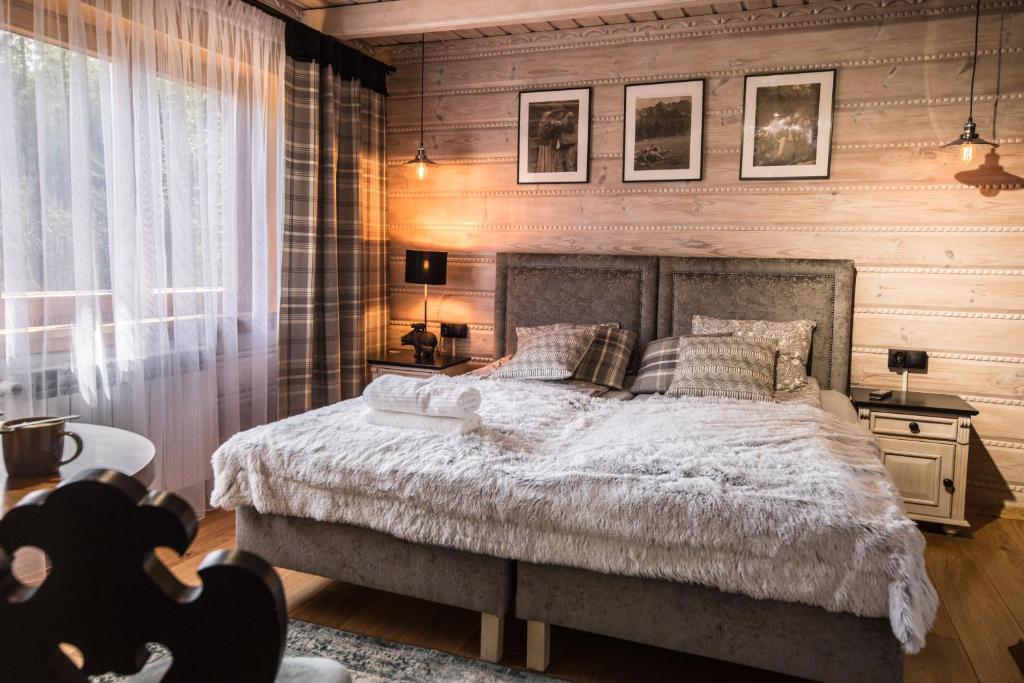 a bedroom with a bed and a wooden wall at Góralska Willa in Nowy Targ