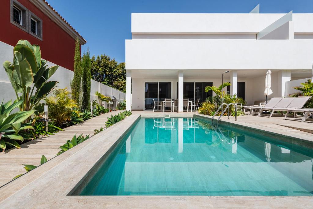 a swimming pool in front of a house at Villa Deluxe Suites Maspalomas in Maspalomas