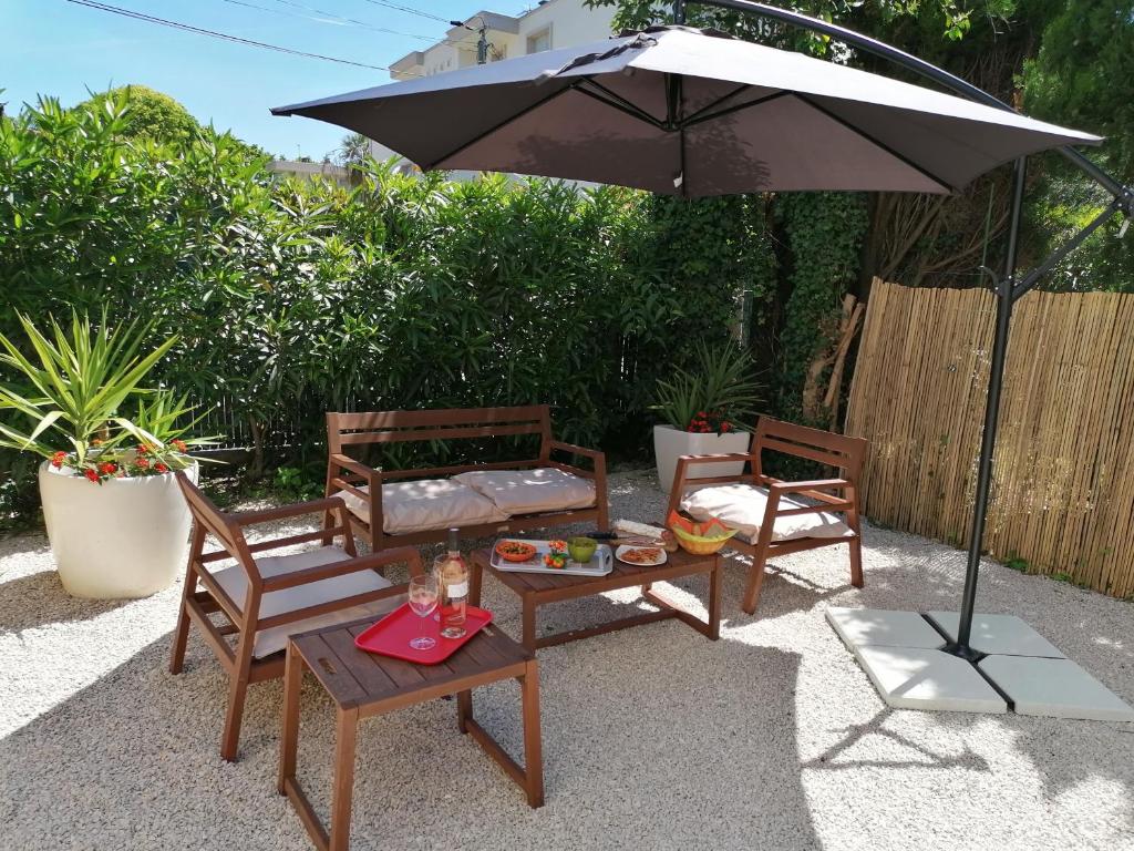 une terrasse avec 2 chaises et une table avec un parasol dans l'établissement 3 min à pieds & 200 m de la Grande Plage des Lecques - Terrasse et Jardin - Fabuleux T2 - Carré d'Or, à Saint-Cyr-sur-Mer