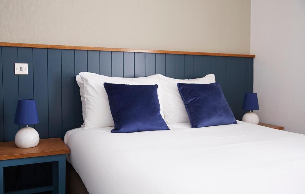 a bed with two blue and white pillows on it at Old Manse Hotel by Greene King Inns in Bourton on the Water
