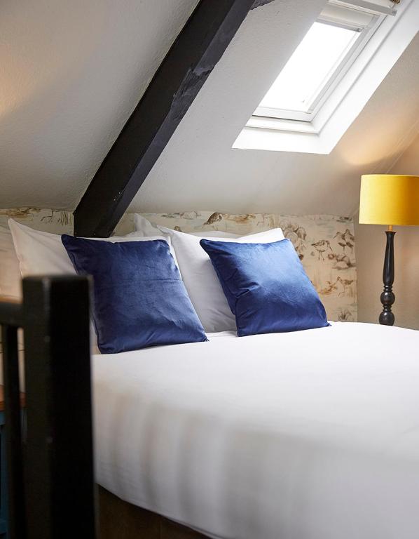 a bedroom with a bed with blue pillows at Old Manse Hotel by Greene King Inns in Bourton on the Water