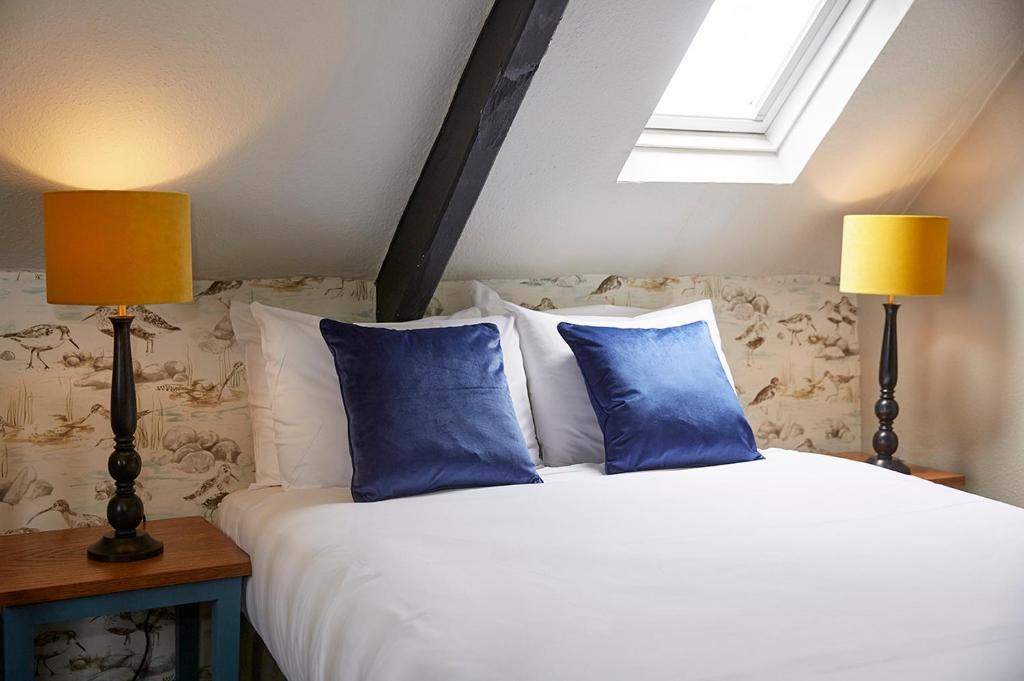 a bedroom with a bed with blue pillows and two lamps at Old Manse Hotel by Greene King Inns in Bourton on the Water