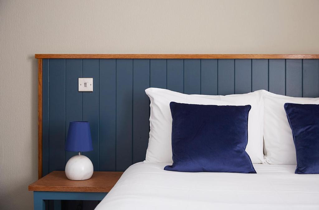 a bed with blue and white pillows and a blue wall at Old Manse Hotel by Greene King Inns in Bourton on the Water