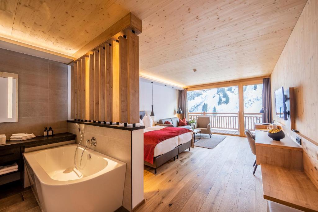 1 dormitorio con 1 cama y bañera en una habitación en Damülser Hof - Wellness & Spa, en Damüls