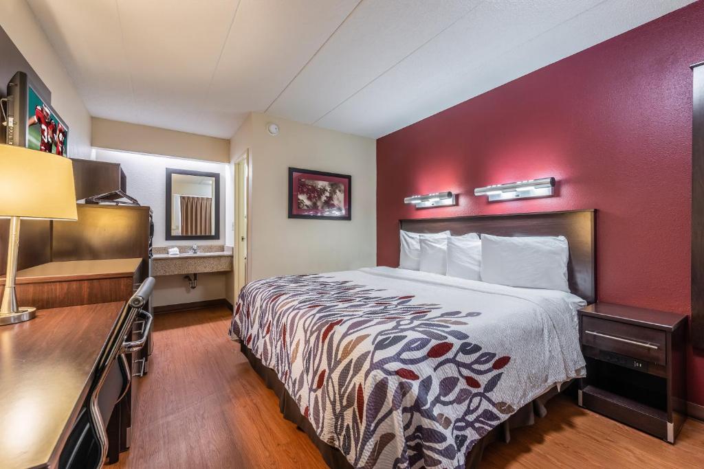 a hotel room with a bed with a red wall at Red Roof Inn Merrillville in Merrillville