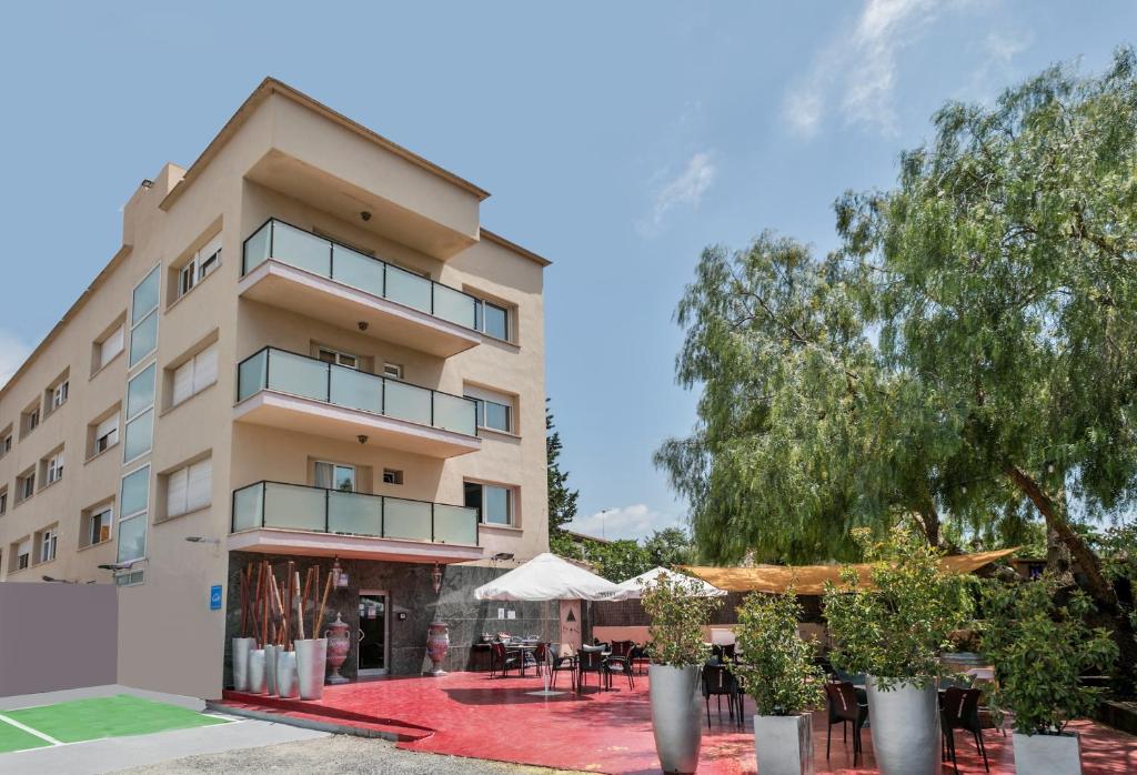 een gebouw met tafels en stoelen ervoor bij Hotel H in Granollers