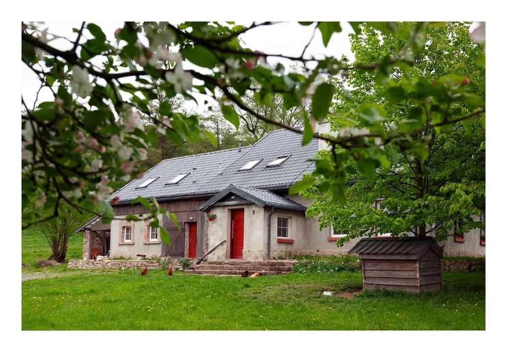 uma casa com uma porta vermelha num quintal em Kozy i Róże em Ołdrzychowice Kłodzkie