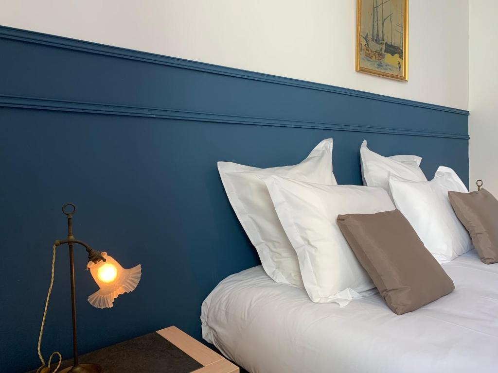 Bett mit blauem Kopfteil und weißen Kissen in der Unterkunft La régate Wimereux - vue mer in Wimereux