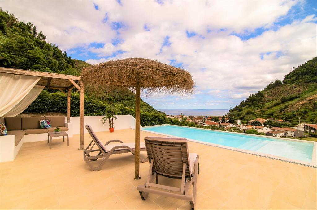 a patio with a table and chairs and a pool at Casa do Outeiro with Heated Pool 30C in Povoação