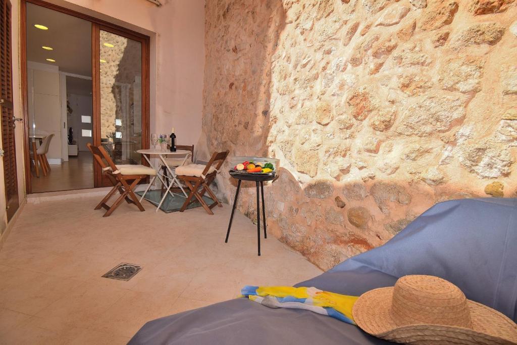 Cette chambre est dotée d'un mur en pierre avec une table et des chaises. dans l'établissement Casa Can Salroig 002 by Mallorca Charme, à Muro