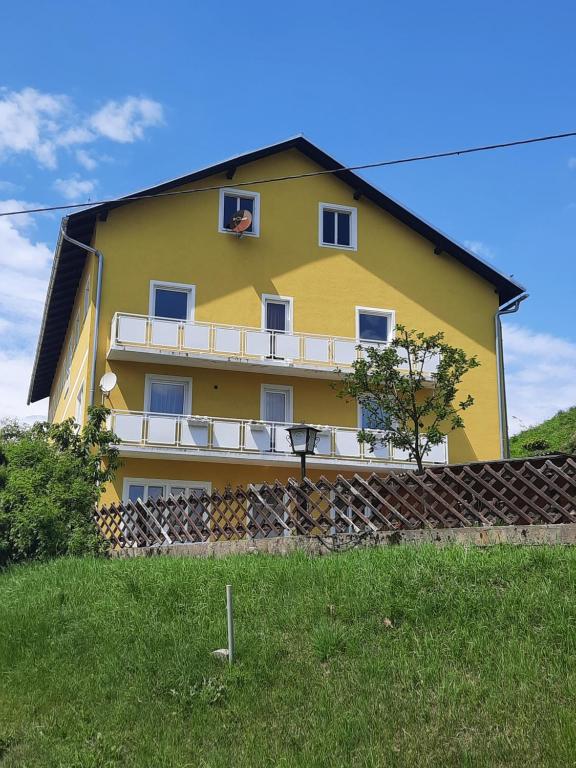 Una casa amarilla con un balcón en el lateral. en Pension Horvath en Sankt Kanzian