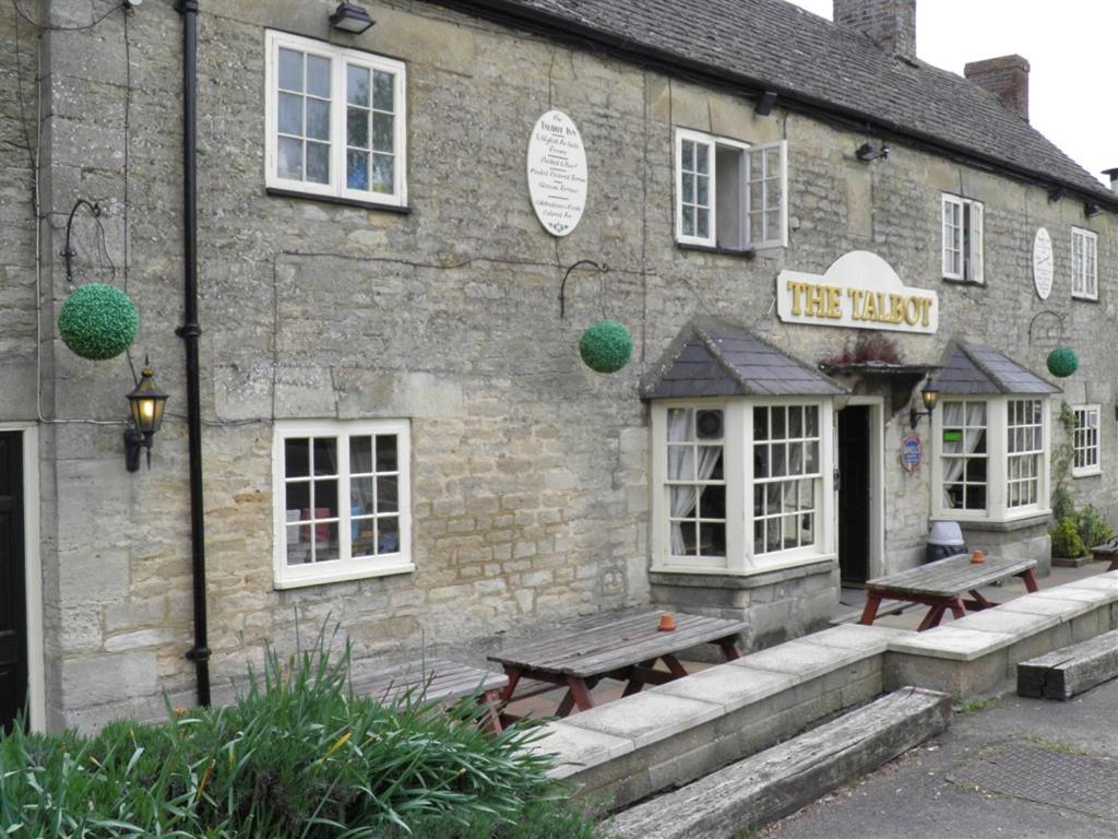 un edificio de ladrillo con dos bancos fuera de él en The Talbot Inn, en Oxford