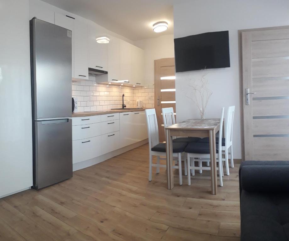 a kitchen and dining room with a table and a refrigerator at Apartament Kąty Rybackie Zaciszna in Kąty Rybackie