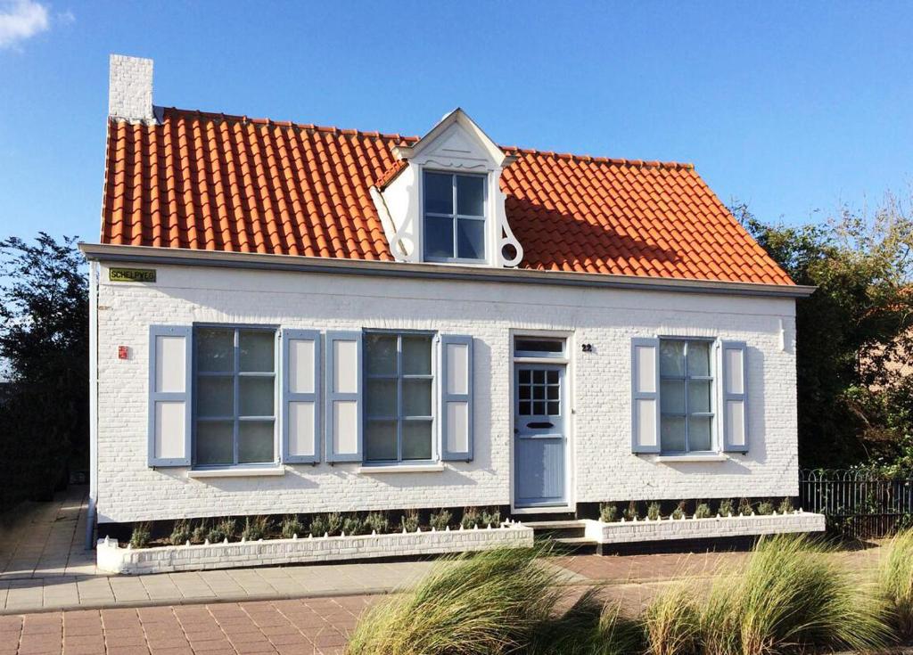 ein kleines weißes Haus mit orangefarbenem Dach in der Unterkunft B&B Zee van Tijd Domburg in Domburg