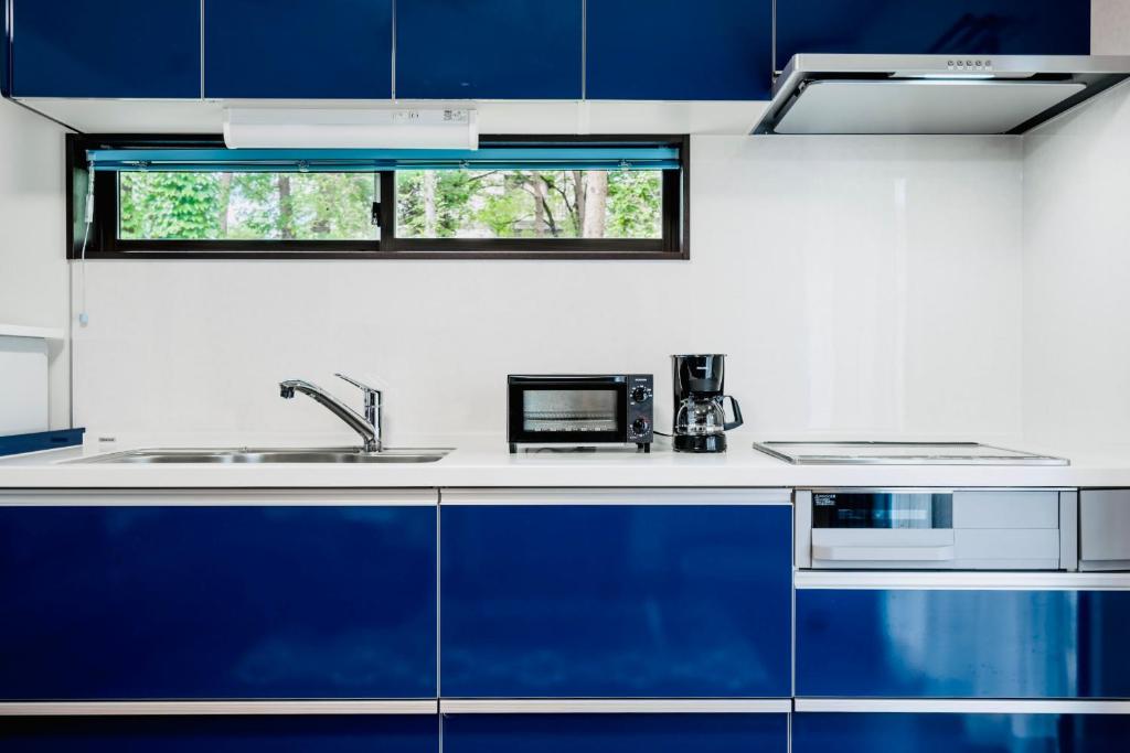 una cocina con armarios azules y fregadero en Sali's House, en Hakuba
