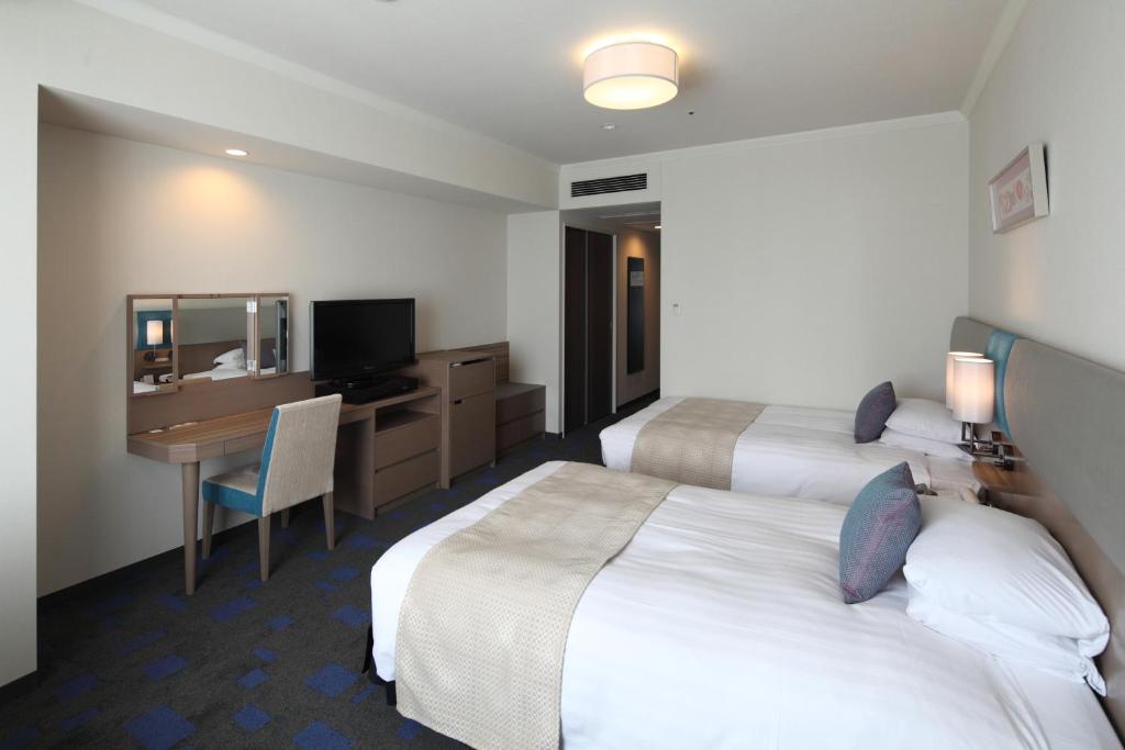 a hotel room with two beds and a desk at Shibuya Excel Hotel Tokyu in Tokyo