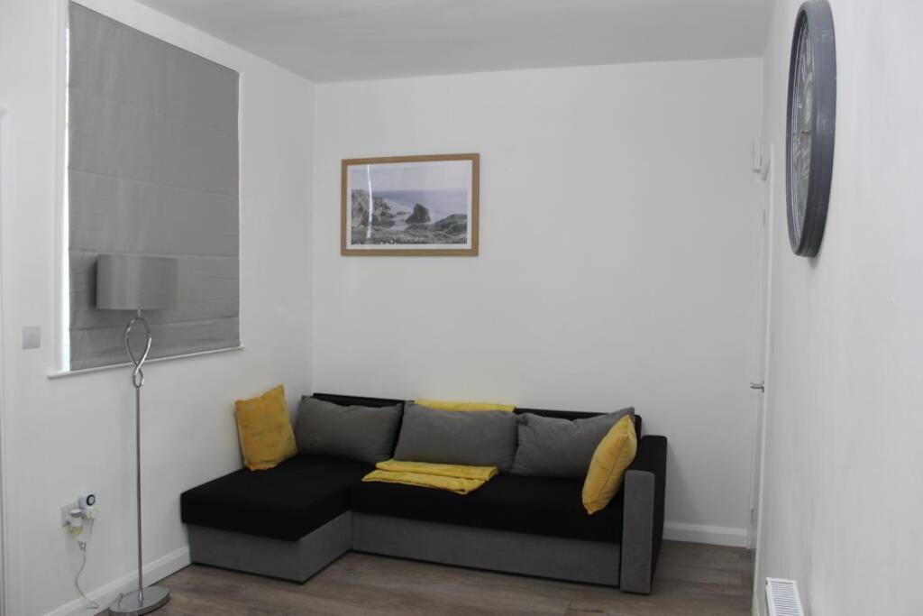 ein Wohnzimmer mit einem schwarzen Sofa und gelben Kissen in der Unterkunft Newly Refurbished 3 Bed 2.5 Bath House in Staines in Staines