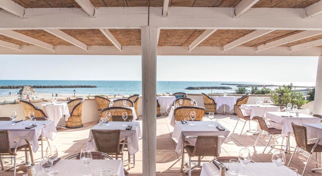 un restaurante en la playa con mesas y sillas en Thalacap Camargue, en Saintes-Maries-de-la-Mer