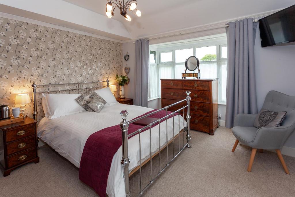 a bedroom with a bed and a chair and a television at Avalon House B&B in Lyndhurst