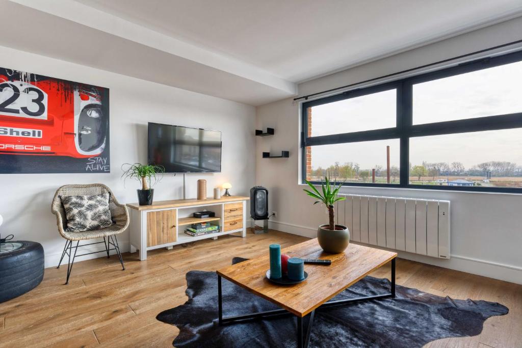 een woonkamer met een tafel en een tv bij L' Annexe du Cosmopolitain in Honfleur