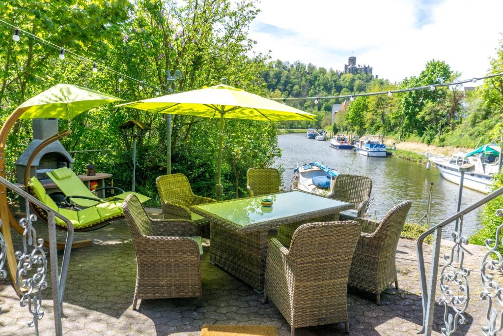 拉恩斯坦的住宿－Ferienhaus auf der Schleuseninsel，河边的桌椅和遮阳伞