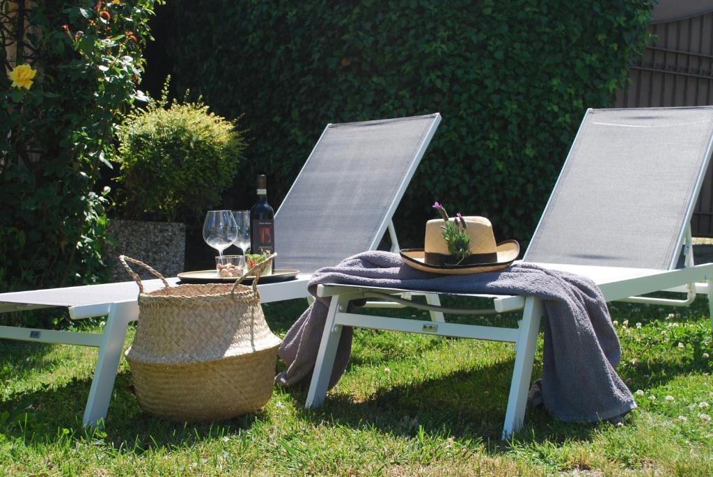 Dos sillas de jardín con sombreros y copas de vino. en B&B Casa Margot, en Neive