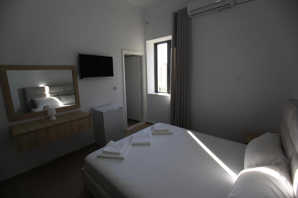 a white bedroom with a bed and a mirror at Bunec Beach Resort in Piqeras