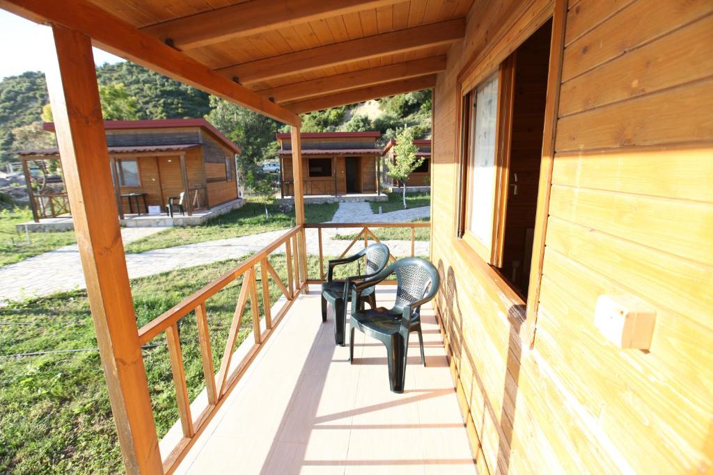 a porch of a cabin with two chairs and a table at Bunec Beach Resort in Piqeras