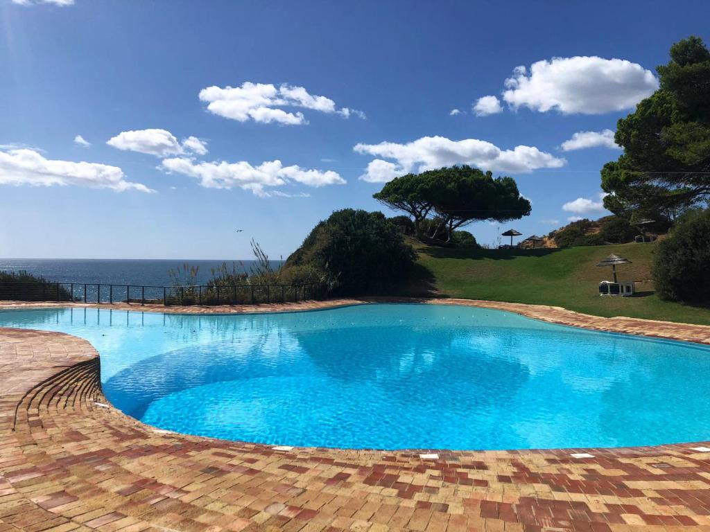 a large blue swimming pool with a view of the ocean at Prainha Lounge in Alvor