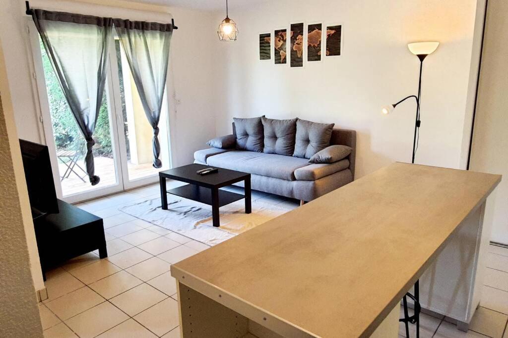 un soggiorno con divano e tavolo di Charmant appartement avec terrasse et jardin au calme Proche Bus Métro a Tolosa
