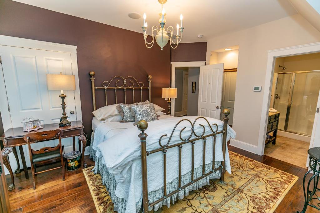 a bedroom with a bed and a table and a chandelier at Riverside Gables Bed and Breakfast in Berea