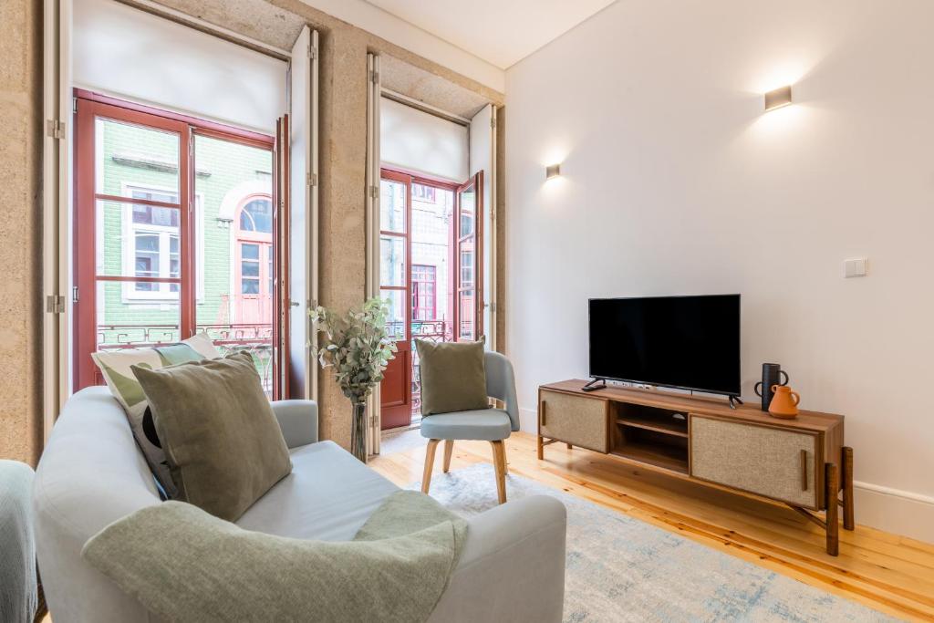 ein Wohnzimmer mit einem Sofa und einem TV in der Unterkunft Sol Downtown Studio in Porto