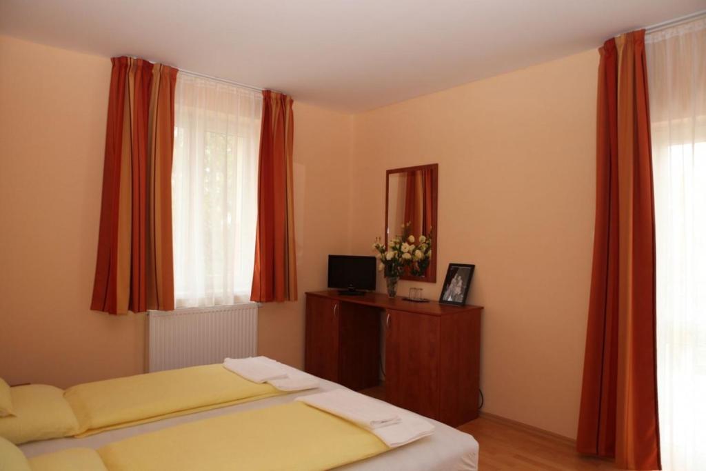 a bedroom with a bed and a window with red curtains at Stan és Panzió in Balatonalmádi