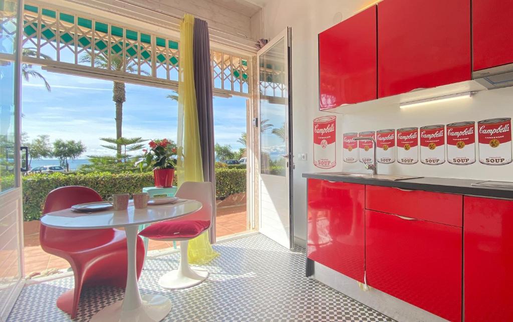 eine Küche mit roten Schränken sowie einem Tisch und Stühlen in der Unterkunft Sunrise Studio Marilyn, vistas jardín y mar in Miami Platja