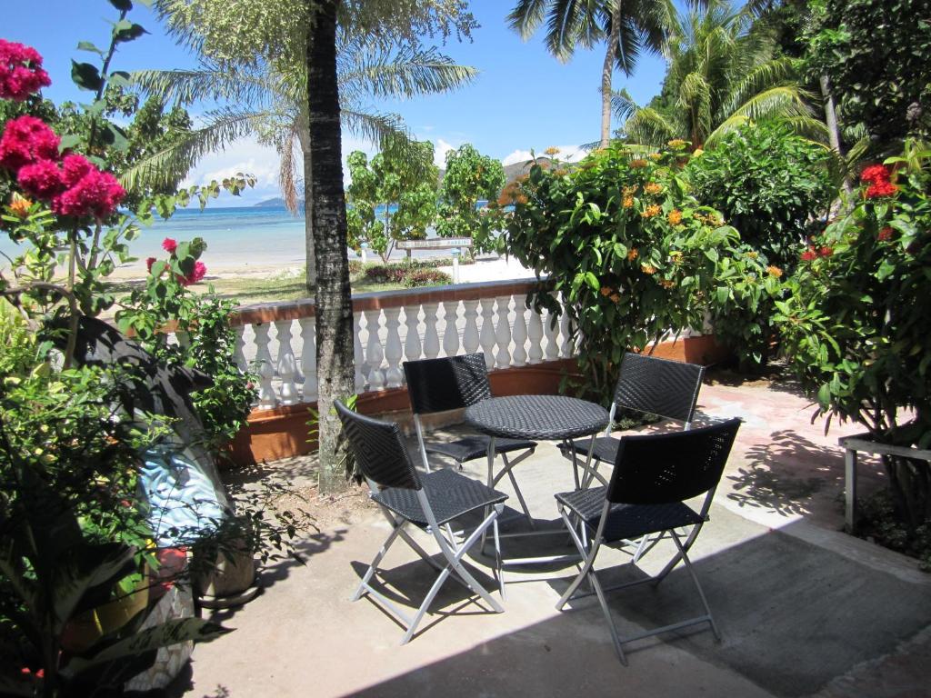 um pátio com uma mesa e cadeiras e a praia em Villa Milou em Baie Sainte Anne