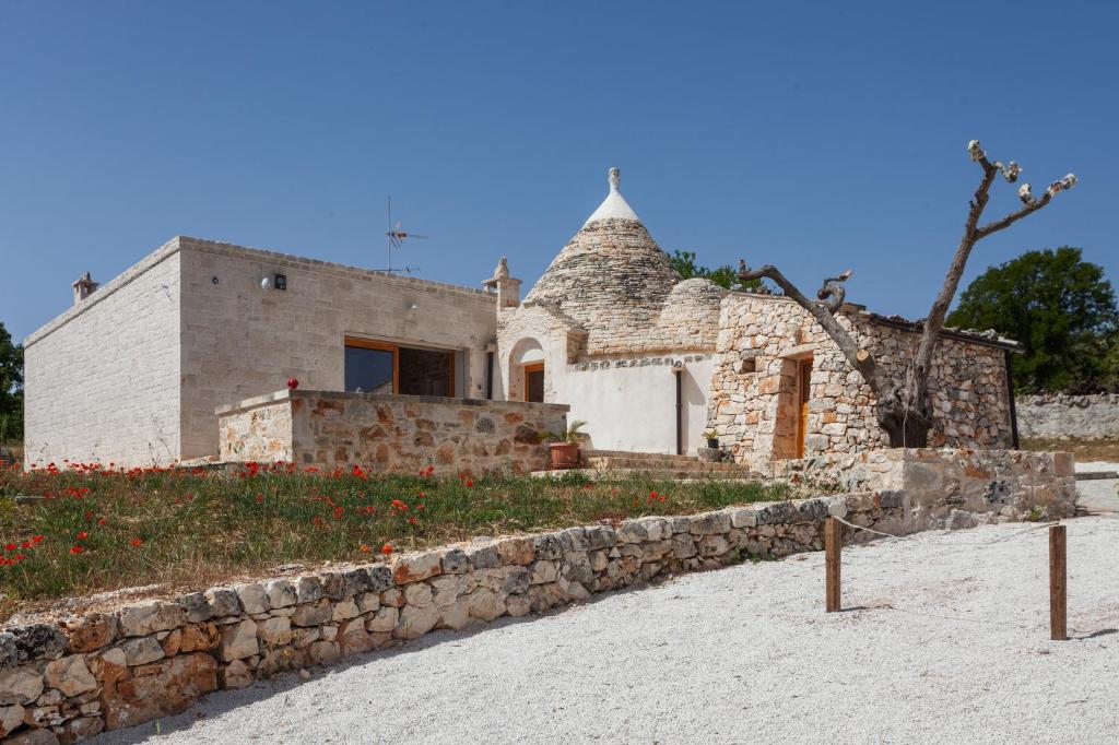 ein Steinhaus am Strand mit einer Steinmauer in der Unterkunft TRUeLLOVE Wonderful Trullo in Putignano in Putignano