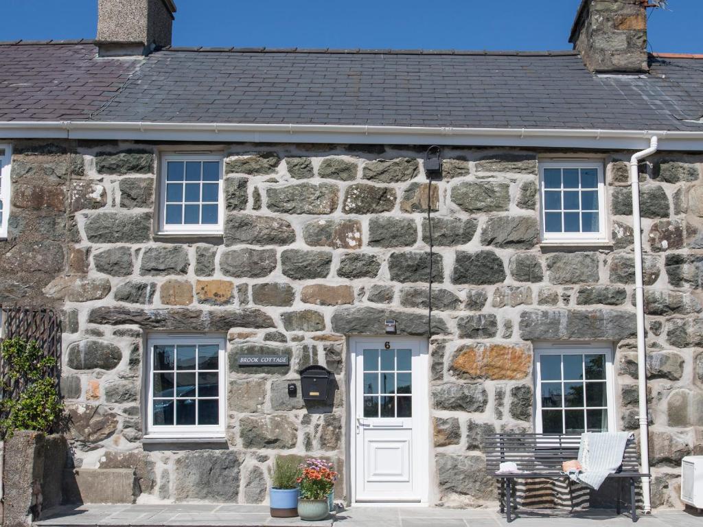 a stone cottage with a white door and windows at Brook Cottage in Criccieth