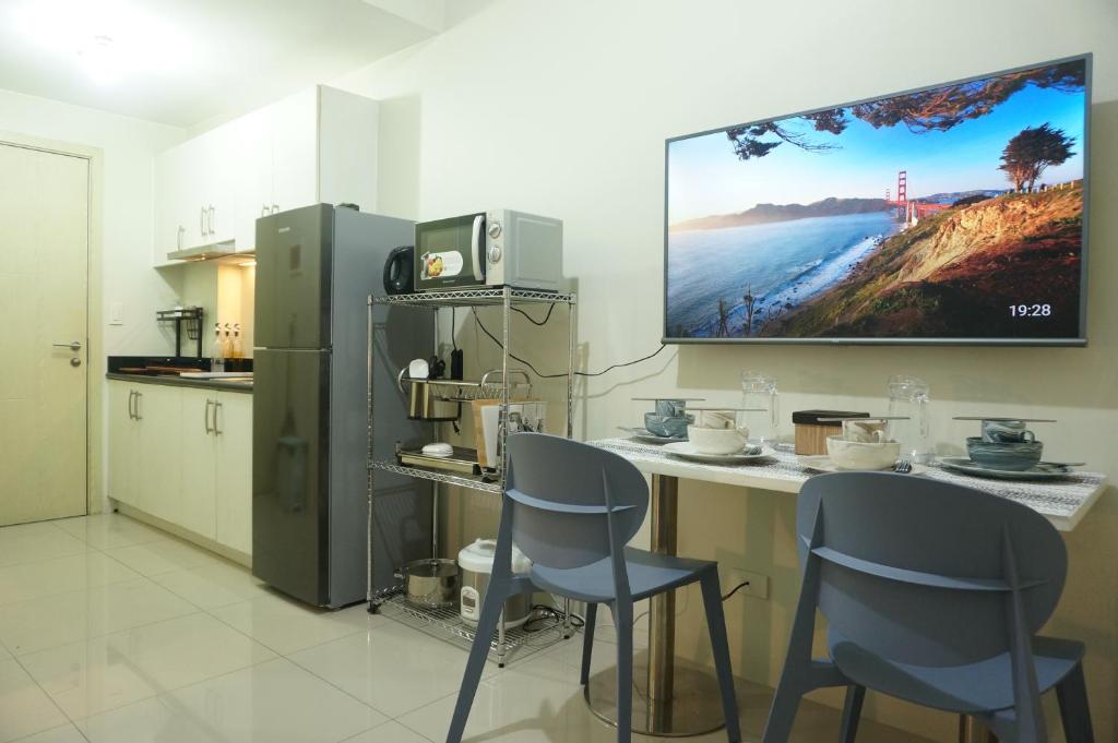 uma cozinha com duas cadeiras e uma televisão na parede em Mint Homes in Jazz Residences Tower B em Manila