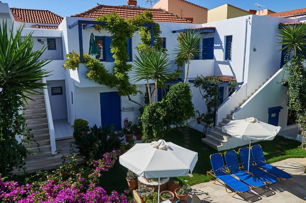 a house with two chairs and umbrellas in front of it at Konaki Studios & Apartments in Panormos Rethymno