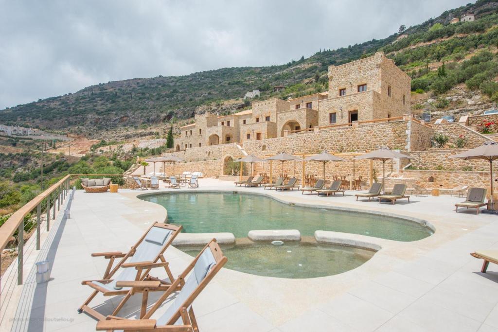 a swimming pool with chairs and a building at Brazzo di Maina in Oitylo