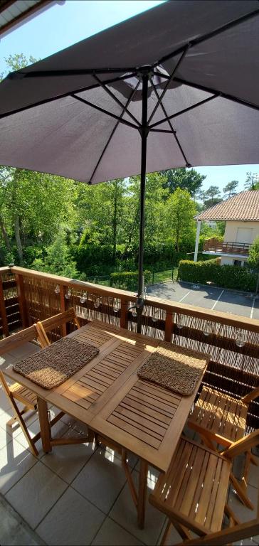 - une table et des chaises sous un parasol sur la terrasse dans l'établissement Appartement 2 chambres Balcon Parking privé Centre Village, à Lit-et-Mixe