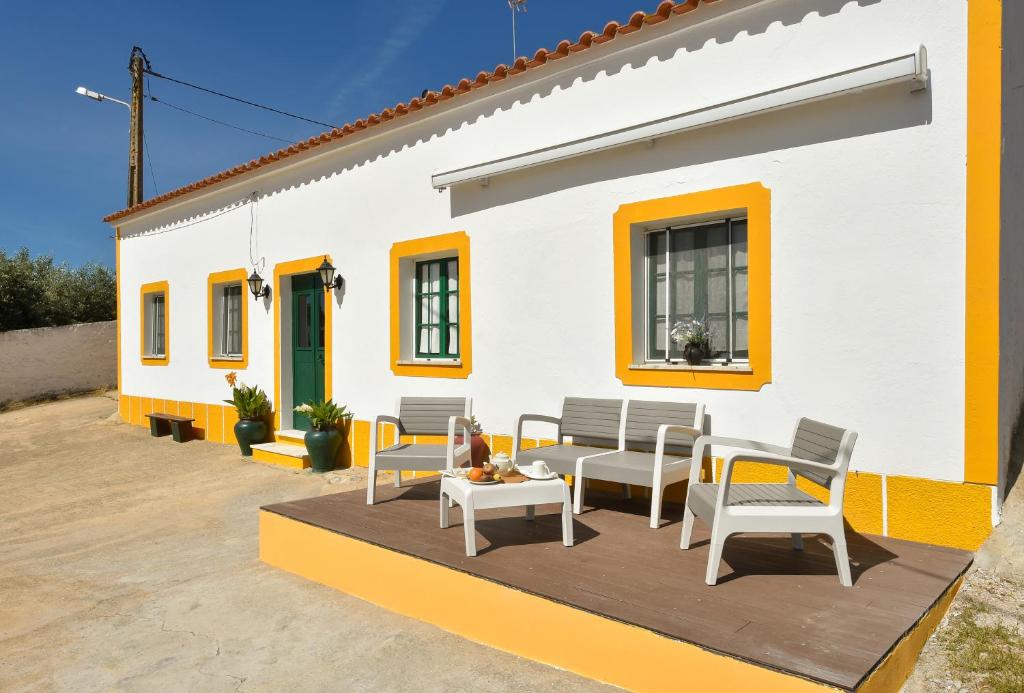 un patio con sedie e tavolo di fronte a una casa di Casa da Aldeia ad Alcaria Ruiva