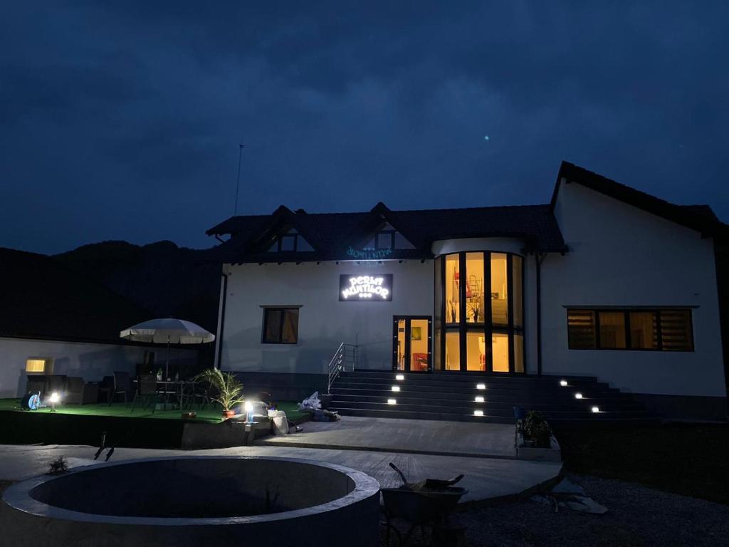 una casa con un letrero iluminado delante de ella por la noche en Perla Muntilor Ponoarele, Padurea de liliac, en Ponoarele