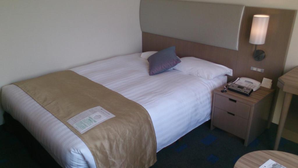 a hotel room with a bed and a phone on a night stand at Shibuya Excel Hotel Tokyu in Tokyo