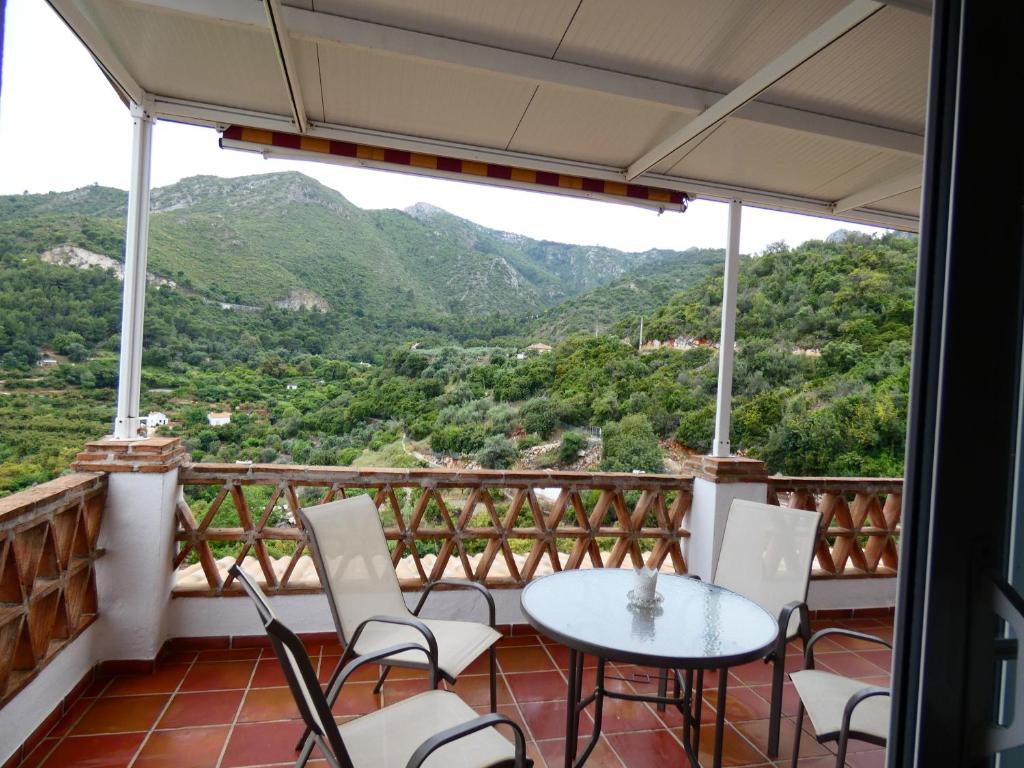 a balcony with a table and chairs and mountains at Alojamientos Monteverde in Ojén